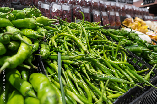 A vibrant display of fresh organic green peppers and raw green beans at a healthy food market offers a spicy vegetarian ingredient for cooking a diet rich in agriculture and natural pods