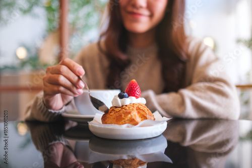 Closeup image of a woman eating cake and drinking coffee in cafe