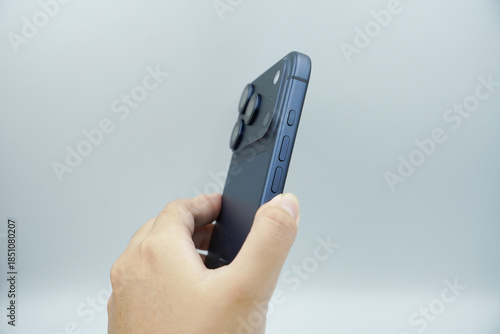 A left hand holds an expensive smartphone in the deep blue variant and shows the volume buttons next to it with a white background.