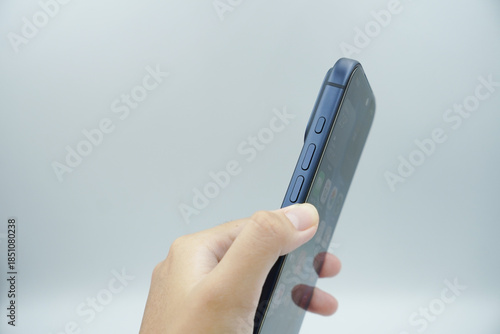 A left hand holds an expensive smartphone in the deep blue variant and shows the volume buttons next to it with a white background.
