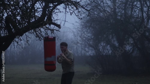 A man in a foggy forest punching a punching bag, a concept of depression and struggle