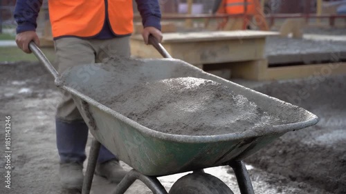 Construction worker transporting concrete using wheelbarrow