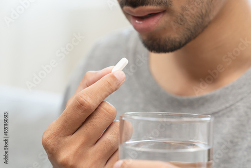 фотографія Young man taking painkiller and drink water to healing from cold flu