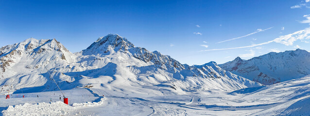 Foto auf Acrylglas Alpen panorama on ski resort  in tarentaise valley, savoie with snowy mountain range and ski slope under blue sky  © coco