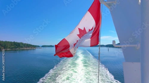 Canadian flag waving on a boat, leaving a trail in the blue ocean in slow motion