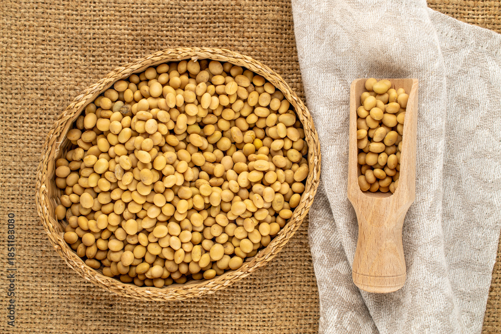 Fototapeta premium Raw soybeans with kitchen utensils on jute cloth, close-up, top view.