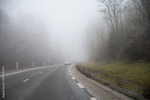 Driving car in thick fog with poor visibility, winter forest on hills, heavy fog and humidity, winter weather conditions