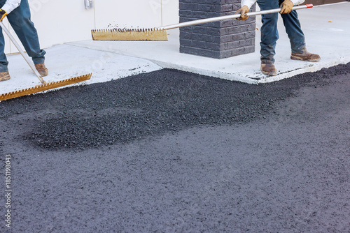 Slika na platnu Construction workers spread hot asphalt on pavement near building road maintenance