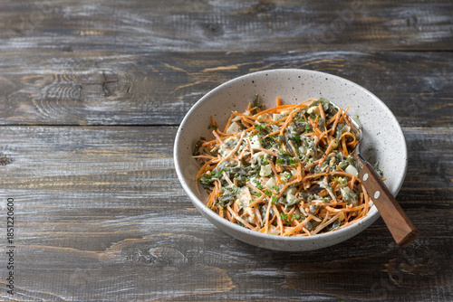 Seaweed and carrot salad mixed with diced egg and creamy dressing in rustic ceramic bowl 