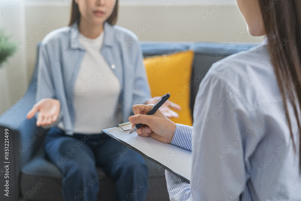 Fototapeta premium Psychology, depression. Suffer asian young woman consultation with psychologist while patient counseling mental therapy, doctor hand taking notes at clinic. Psychologist with sick mental health person
