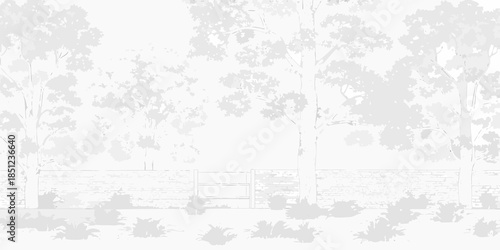 A grayscale view of trees and a low stone wall in a park setting