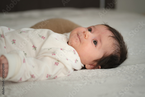 peaceful newborn baby lying on bed at home in soft natural light.