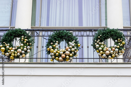 Three Christmas wreaths on the balcony of an office building.