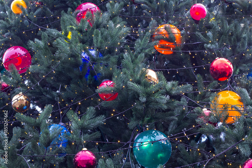 A Christmas tree with colorful balls and garland. Part of the frame.