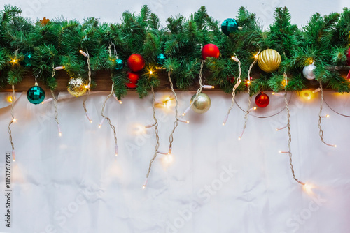 New Year's background. Fir branches with baubles and a glowing garland on a white background.