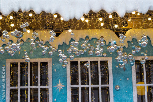 Christmas decoration: A decorative house with windows, twinkling lights, and silver balls. Part of the frame.