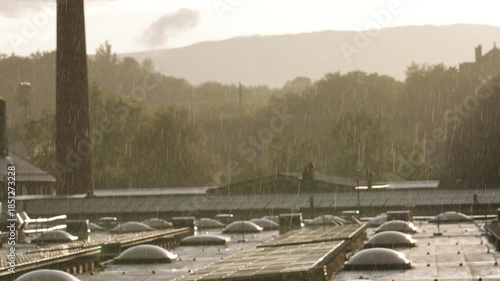 Slow motion sun shower rain over an industrial rooftop at sunset