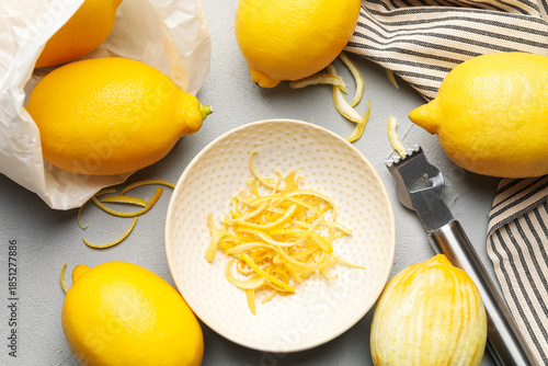 Cuadro en lienzo Fresh lemons with zest and zester tool on grey table, flat lay