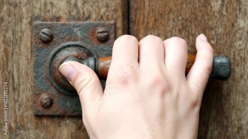 Detailed view of an old door handle with a keyhole, attached to a weathered wooden door, showcasing the texture and design of vintage hardware during daylight