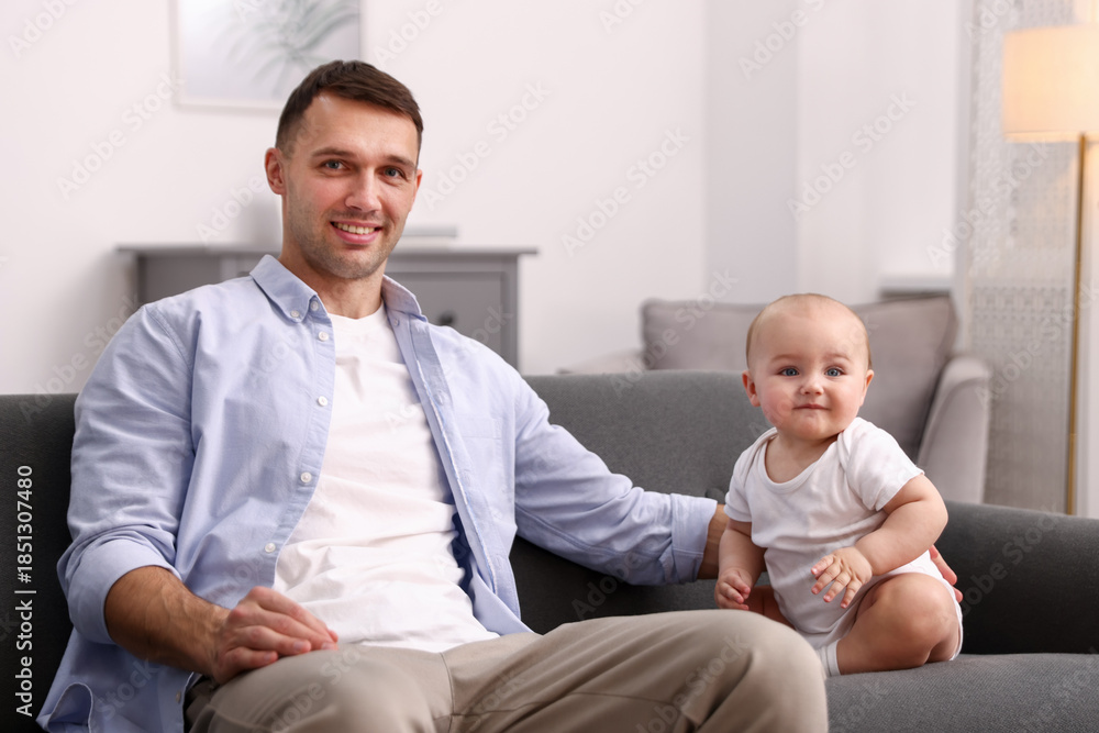 Fototapeta premium Happy father with his cute baby on sofa at home