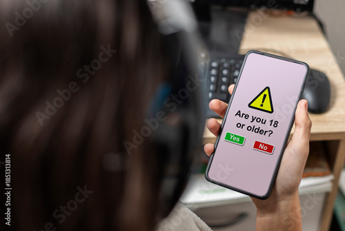 Fotografie A teen holding a mobile with age verification
