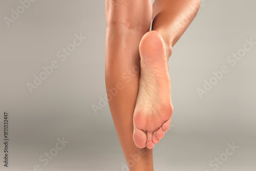 Schilderij op canvas Studio shot of a woman’s tanned legs with one raised bare foot, posing and clear