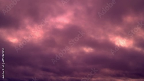 Dramatic purple clouds moving across the sky during a beautiful boreal sunrise on the shortest day of the winter, revealing glimpses of the bright, warm sun behind the thick cloud cover, timelapse