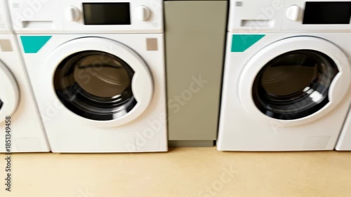 Row of modern white washing machines with digital displays in a laundry room, viewed from a high angle on a beige floor