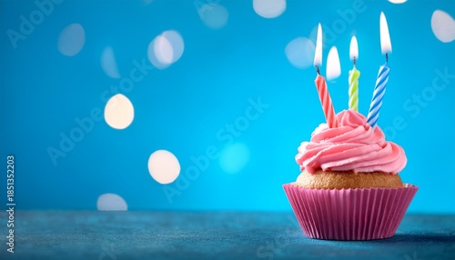 birthday cupcake with 3 candles on blured blue background with big empty copyspace