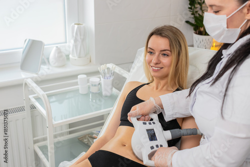 Картината върху платно Middle-aged woman girl lies calmly during LPG vacuum roller massage on abdomen performed by cosmetologist