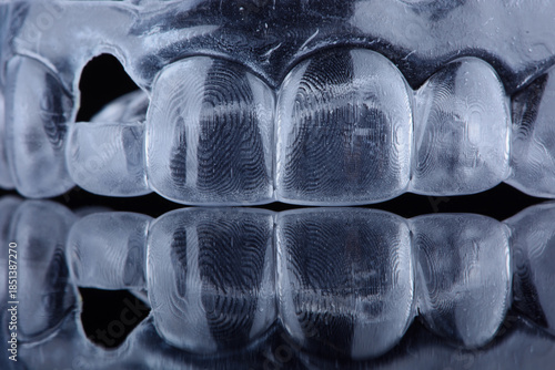 Printed transparent dental cap made of polymer on a light colorful background. Dental splint against bruxism.