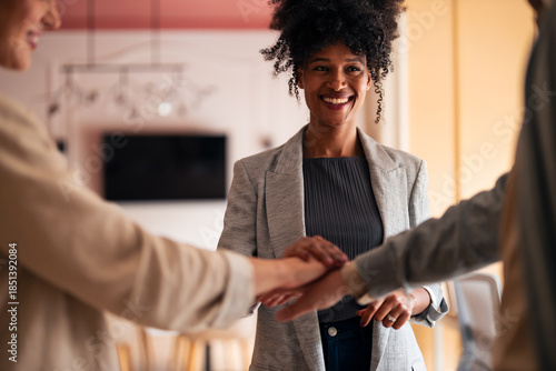 Fotografie Smiling Woman Leads Team Huddle as Hands Stack in Office Meeting