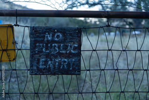 A rustic No Public Entry sign on a wire fence