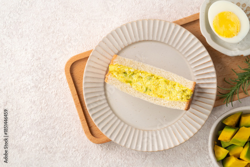 Healthy avocado and egg salad sandwich on white plate for breakfast