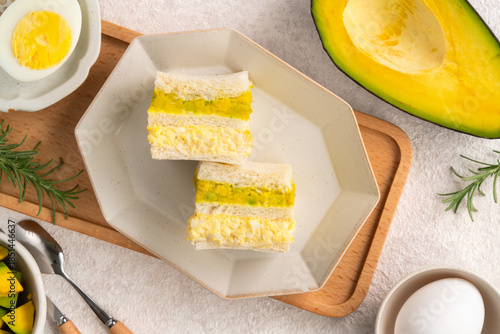 Healthy avocado and egg salad sandwich on white plate for breakfast