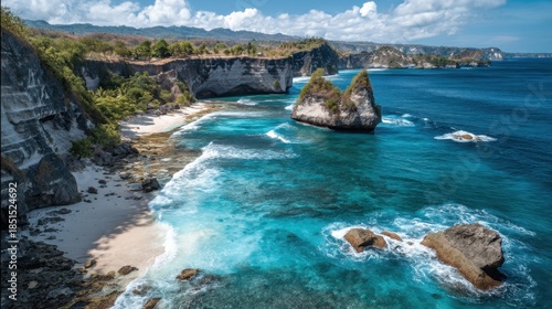 Cliffs rise steeply from a beach with soft sand and clear water. Rocky formations dot the coastline under a bright blue sky. The scene shows waves breaking along the shore.