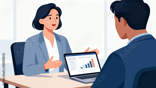 A woman and a man are sitting at a table with a laptop in front of them. The woman is talking to the man, and they are both looking at the laptop screen. The laptop screen shows a graph with numbers