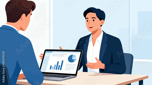 Two men are sitting at a table with a laptop in front of them. One man is holding the laptop and the other man is looking at it. Scene is professional and focused