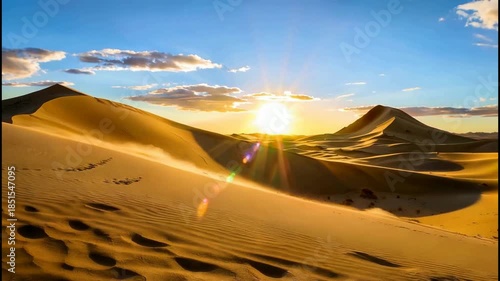 Golden Sunset Over Vast Desert Dunes with Clear Blue Sky and Scattered Clouds.