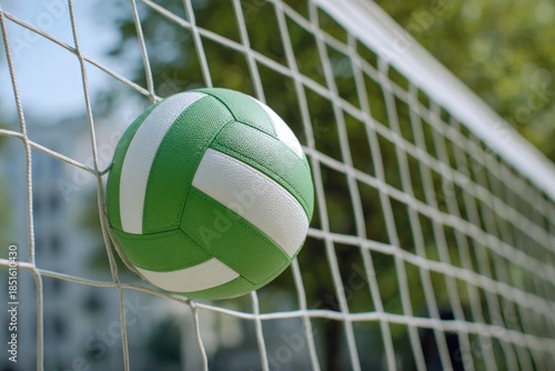 A vibrant green and white ball is momentarily caught within the taut strings of a net, suggesting a decisive moment in an outdoor game. The sharp focus on the ball's textured surface and the intricate