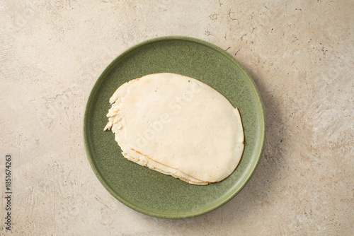 A top down view of a plate of chicken breast deli slices.