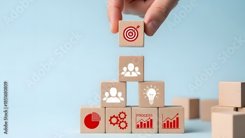 Hand placing a final wooden block with a target icon representing business strategy completion