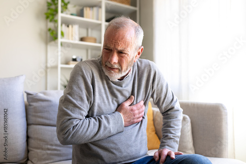 Senior man suffering heart attack on sofa at home