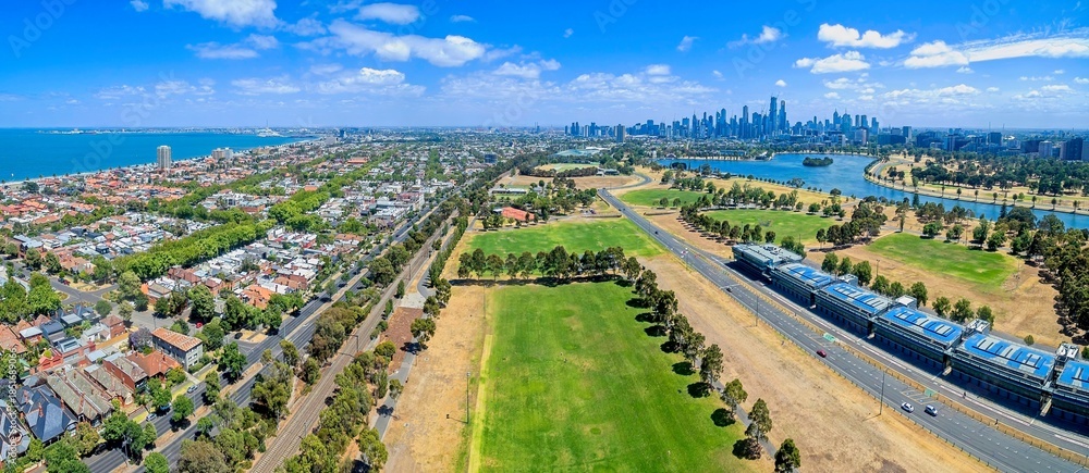 Fototapeta premium An aerial view of the Albert Park Grand Prix Circuit infrastructure, featuring the pit lane buildings and track. The view extends over Albert Park Lake toward