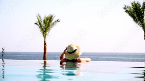 Woman in the pool by the sea at sunrise or sunset