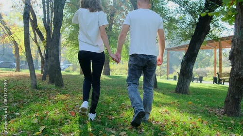 A man and woman walk hand in hand through a lush green forest surrounded by trees. Perfect 4K video for romance, travel, nature, and lifestyle content.
