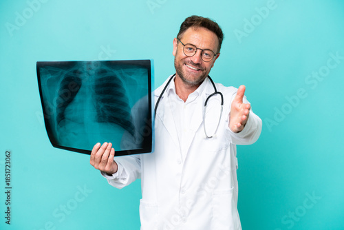 Фотография Middle age professional traumatologist doctor man isolated on blue background sh