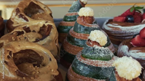 Close-up of assorted gourmet pastries including cream-filled rolls and fruit-topped desserts in a bakery display, perfect for premium food and bakery concepts.