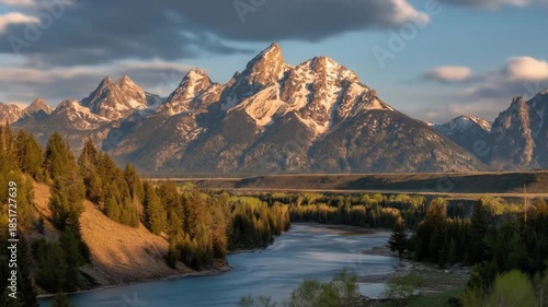 Majestic mountain range with river flowing through lush valley landscape