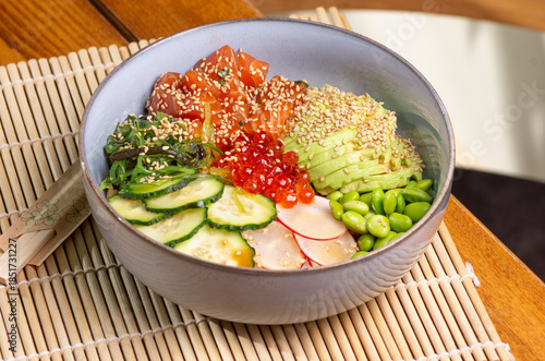 Healthy Poke bowl with salmon and caviar on wooden background.